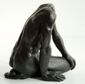 dexter lateral view of a sculpture of a male nude sitting on his knees