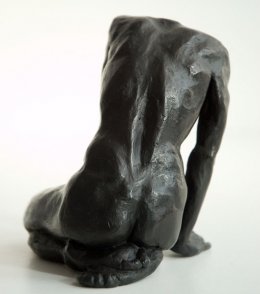 dorsal view of a sculpture of a male nude sitting on his knees