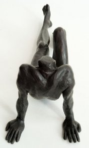 view of a bronze sculpture of a male nude sitting and leaning back on his arms