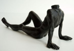 lateral dorsal view of a bronze sculpture of a male nude sitting and leaning back on his arms