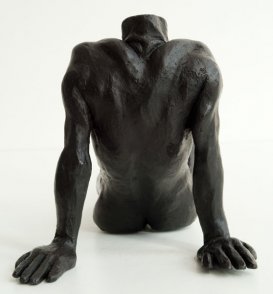 dorsal view of a bronze sculpture of a male nude sitting and leaning back on his arms