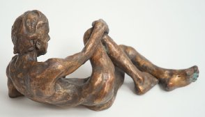lateral view of bronze sculpture of a male nude leaning on his ellbow