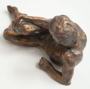cranial view of bronze sculpture of a male nude leaning on his ellbow