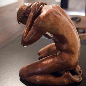 Bronze sculpture of a male nude kneeling down