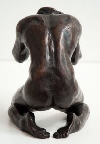 dorsal view of a bronze sculpture of a male nude kneeling down