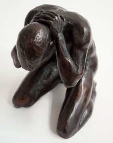 sinister lateral frontal cranial view of a bronze sculpture of a male nude kneeling down