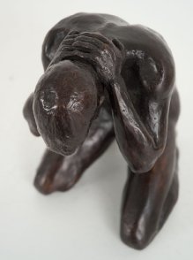 cranial frontal lateral view of a bronze sculpture of a male nude kneeling down