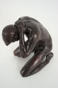 cranial lateral frontal view of a bronze sculpture of a male nude kneeling down