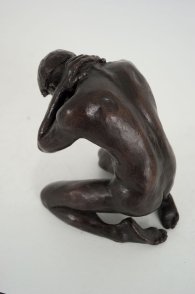 cranial lateral dorsal view of a bronze sculpture of a male nude kneeling down