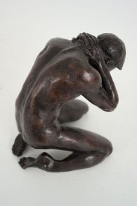 cranial lateral dorsal view of a bronze sculpture of a male nude kneeling down