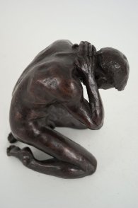 cranial lateral view of a bronze sculpture of a male nude kneeling down