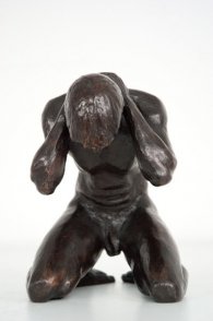 frontal view of a bronze sculpture of a male nude  kneeling down
