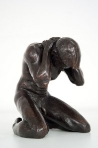 frontal lateral view of a bronze sculpture of a male nude kneeling down
