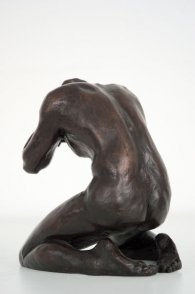 dorsal lateral view of a bronze sculpture of a male nude kneeling down