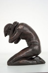 lateral view of a bronze sculpture of a male nude kneeling down