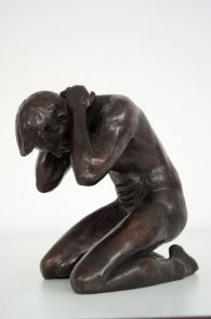 lateral frontal view of a bronze sculpture of a male nude kneeling down