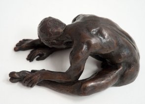 sinister lateral view of a bronze sculpture of a male nude sitting with his head on his knee