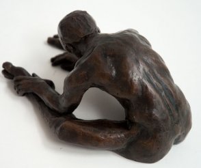 dorsal sinister lateral view of a bronze sculpture of a male nude sitting with his head on his knee