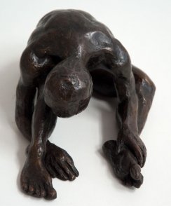 frontal view of a bronze sculpture of a male nude sitting with his head on his knee