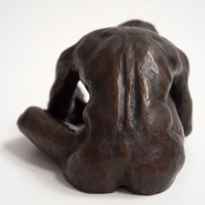 dorsal view of a bronze sculpture of a male nude sitting with his head on his knee
