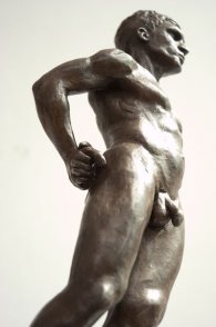 caudal lateral frontal view of bronze sculpture of male nude standing figure