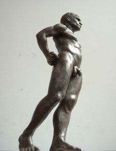 caudal lateral frontal view of bronze sculpture of standing male nude figure